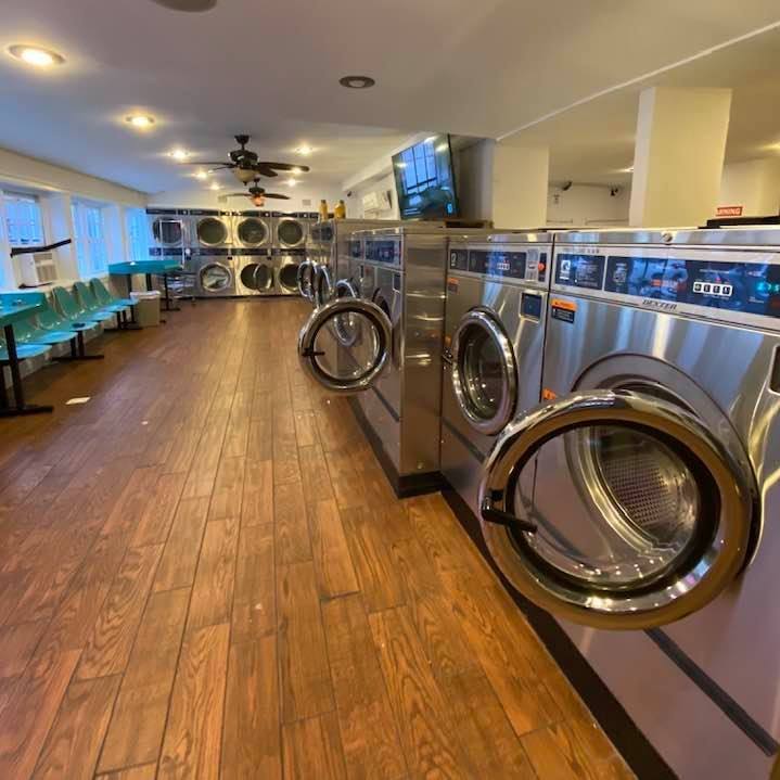 Modern self service laundromat in Frederick MD with multiple washing machines and folding benches open 24/7