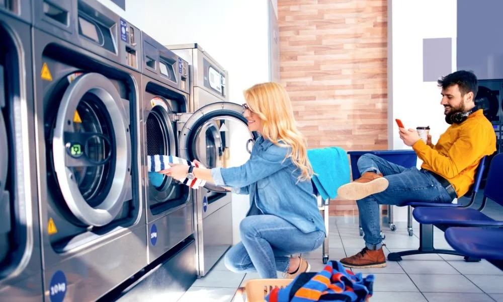 Two professionals discussing commercial laundry services and laundry management near a washing machine for local business needs