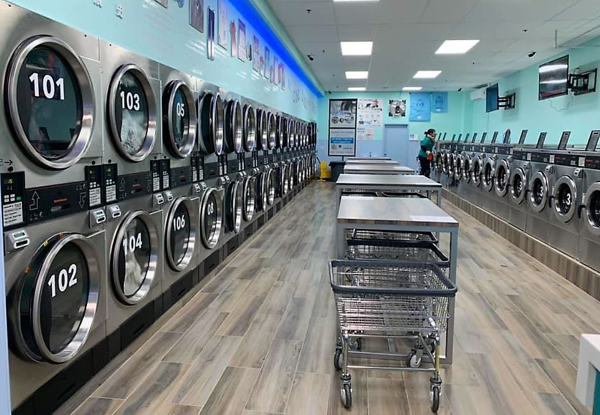 Commercial laundry room with multiple washing machines and laundry cart at 4th Street Laundromat in Frederick MD