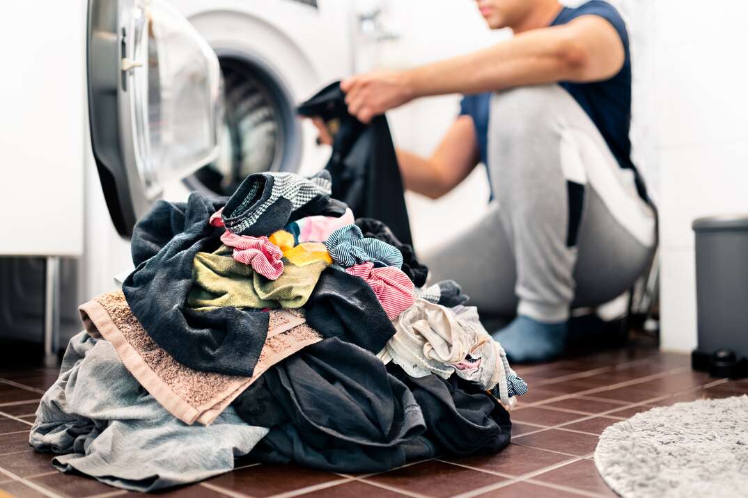 Man placing clothes into a laundry basket for vacation rental laundry service