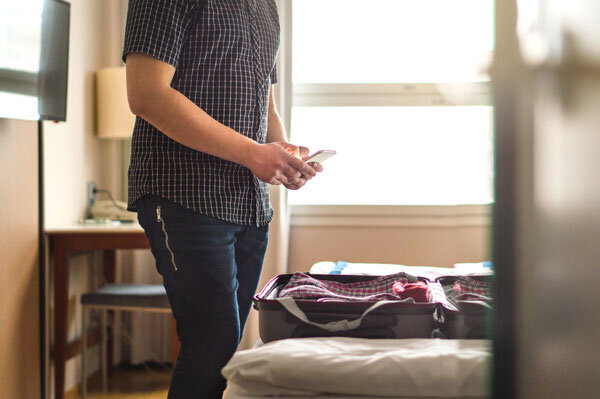 Man standing beside a suitcase ready for short-term rental guest travel
