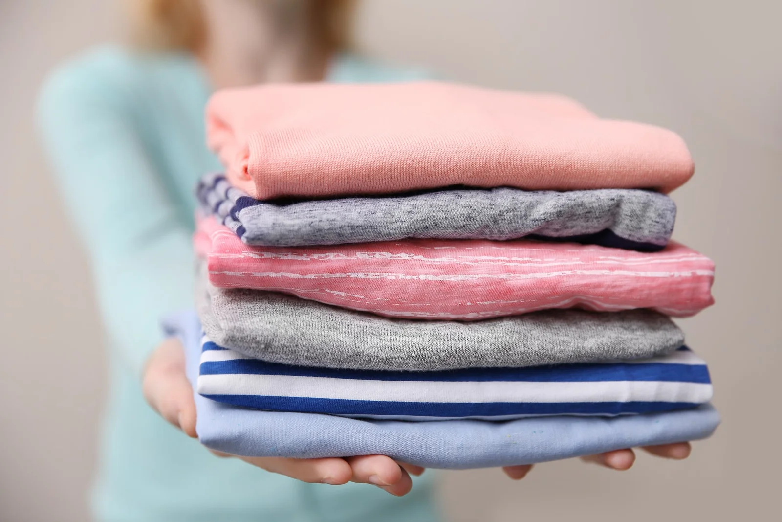Woman holding neatly folded clothes for Airbnb wash and fold laundry service