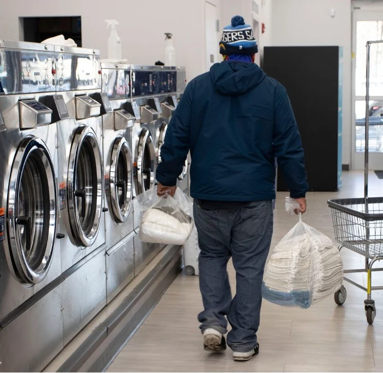 Man carrying a bag of laundry in a commercial laundry room in Frederick MD