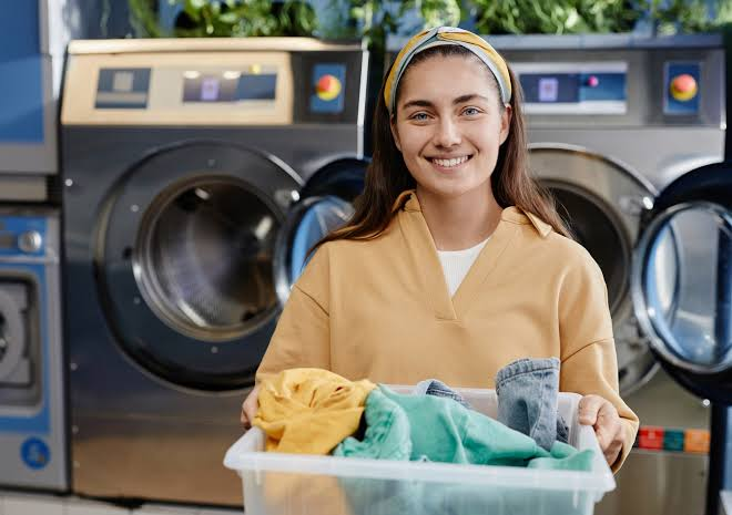 Woman holding a basket of freshly laundered clothes at a washing machine in Frederick MD